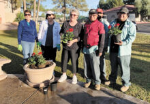 Garden Club members Laurie Doyle, Shelly Seel, and Gudie Huffman with SunBird Golf maintenance crew, planting geraniums by the fountain.