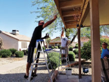 Steve Seel and Bob Bitler paint the trim on an elderly neighbor’s home