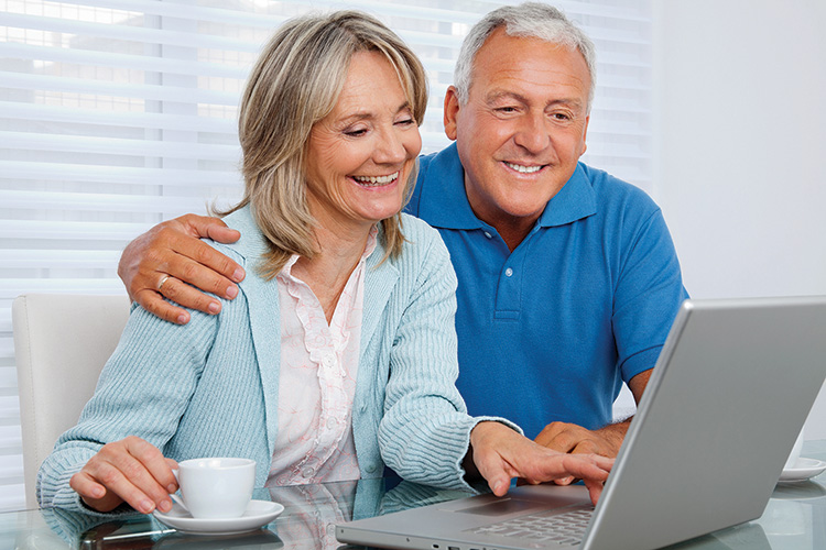 Mature woman having tea and browsing internet with her husband on laptop